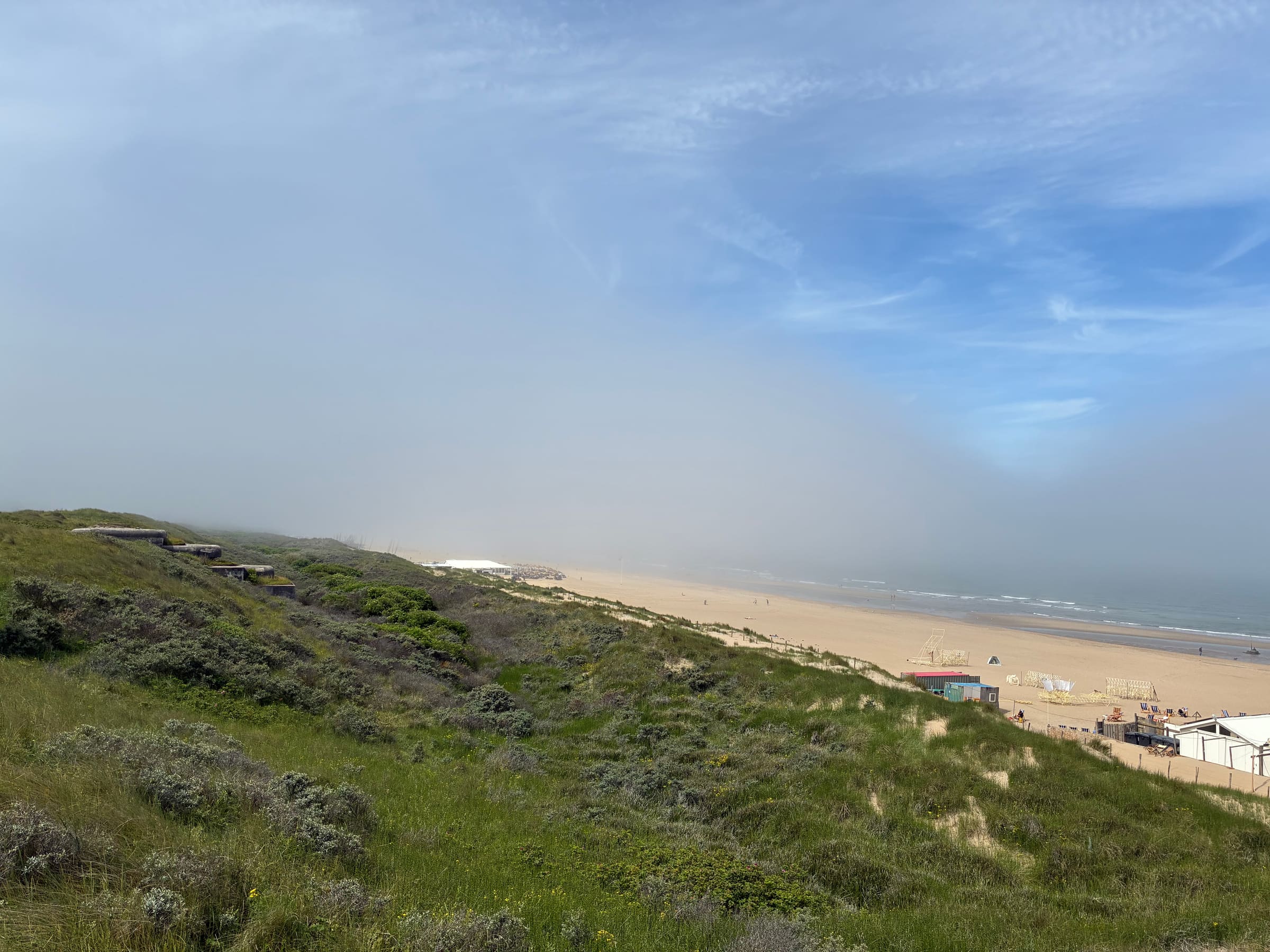 Dune grass overlooking a wide North Sea beach near The Hague, with WWII-era bunkers along the dune ridge